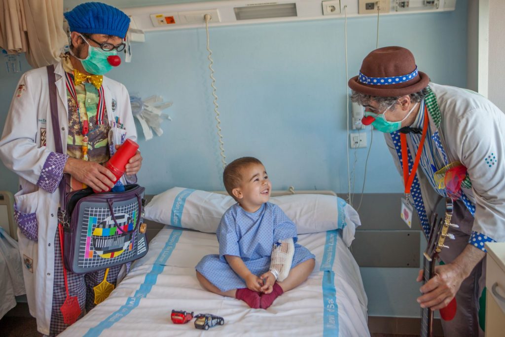 Payasos de sonrisa médica con un niño hospitalizado.